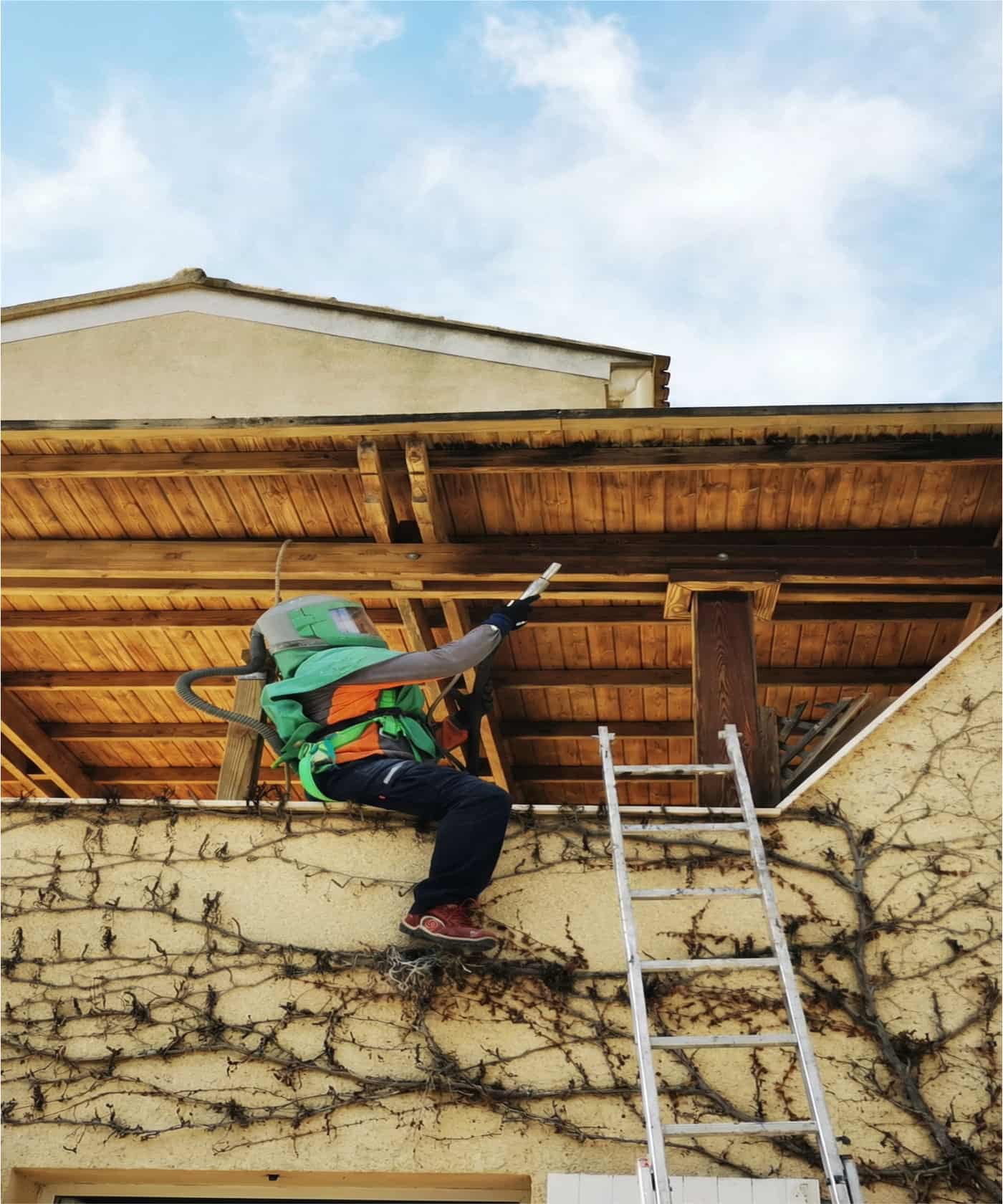 Operario limpiando una tarima de madera exterior con hidrolimpiadora, mostrando el área mojada y el resultado.